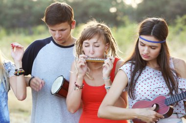 Müzik aletleri ormandaki açık havada oynarken mutlu gülümseyen arkadaşlar
