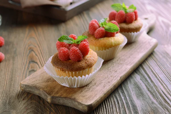 Deliciosos cupcakes con bayas y menta fresca en la mesa de madera de cerca —  Fotos de Stock