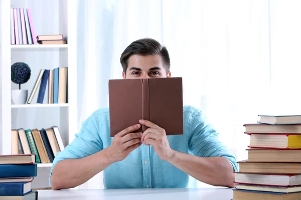 Jovem homem lendo livro à mesa — Fotografia de Stock