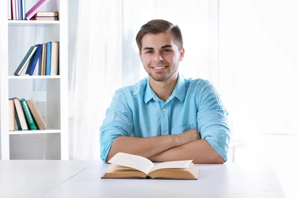 Genç adam masada kitap okumak — Stok fotoğraf