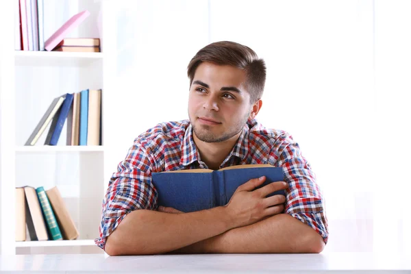 Jovem homem lendo livro à mesa — Fotografia de Stock