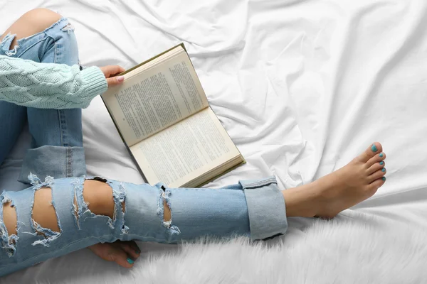 Vrouw in spijkerbroek op bed — Stockfoto