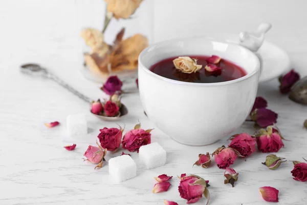 Tea and tea rose flowers on table closeup