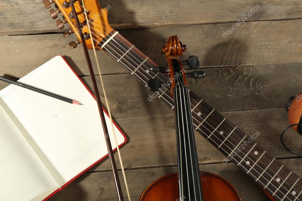 Electric guitar, violin, soprano saxophone and book on wooden background
