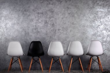 Gri arka plan üzerinde beyaz ve siyah sandalye ile şık anlayışı