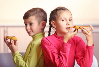 Çocuklar pizza yiyor.  