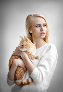 kadın kırmızı kedi elinde tutar.