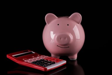 Koyu arka plan üzerinde hesap makinesi ile Piggy banka