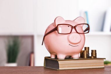 Kumbara gözlük kitap ve ev ya da ofis arka plan üzerinde para ile