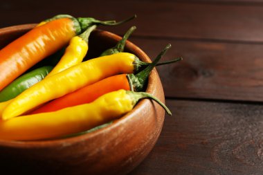 Kase koyu ahşap arka plan üzerinde renkli biber