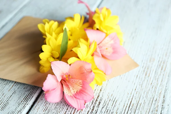 Rosa alstroemeria och gula krysantemum i kuvert på trä bakgrund — Stockfoto