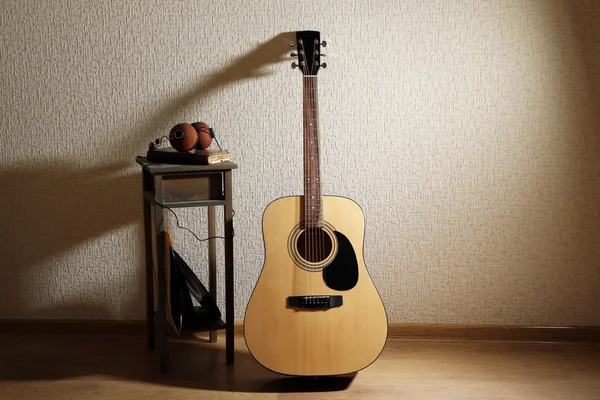 Acoustic guitar propped on wall with stool and headphones on it in the room — Stock Photo, Image