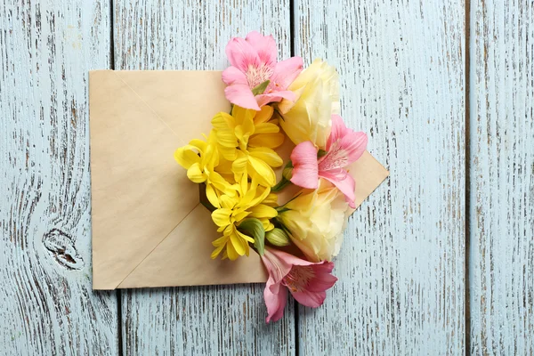 Verse boeket van bloemen in envelop op houten achtergrond — Stockfoto