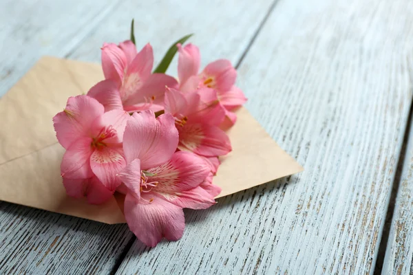 Pink alstroemeria in envelope on wooden background — Stock Photo, Image