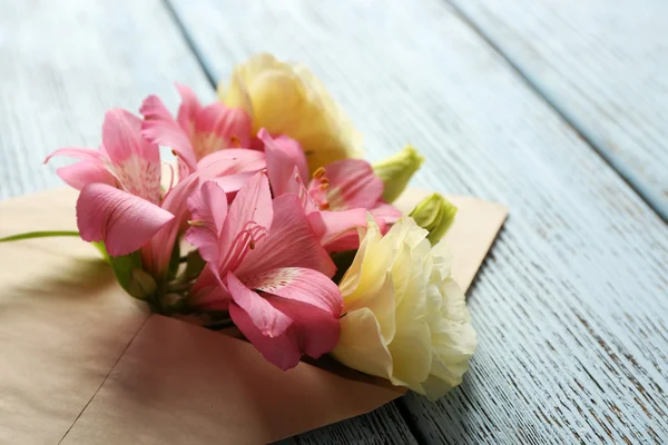 Beyaz eustoma ve ahşap arka plan üzerinde zarf içinde pembe alstroemeria — Stok fotoğraf