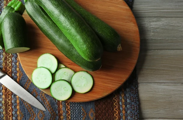 Fresh sliced zucchini on cutting board, on wooden background — Stock Photo, Image