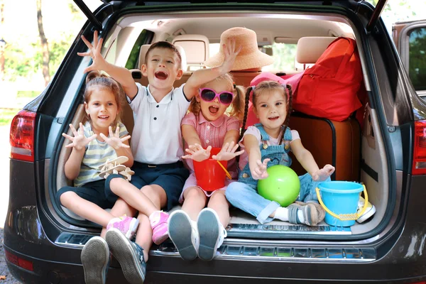3 つの美しい女の子と男の子が車の上に座るトランクと笑って — ストック写真