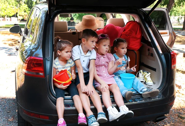 Enfants heureux assis sur le coffre de la voiture — Photo