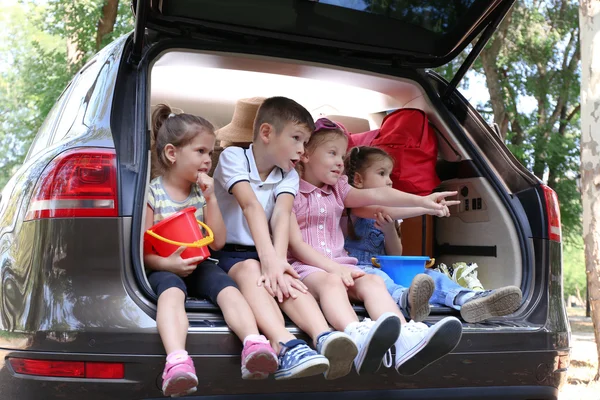 Enfants heureux assis sur le coffre de la voiture — Photo