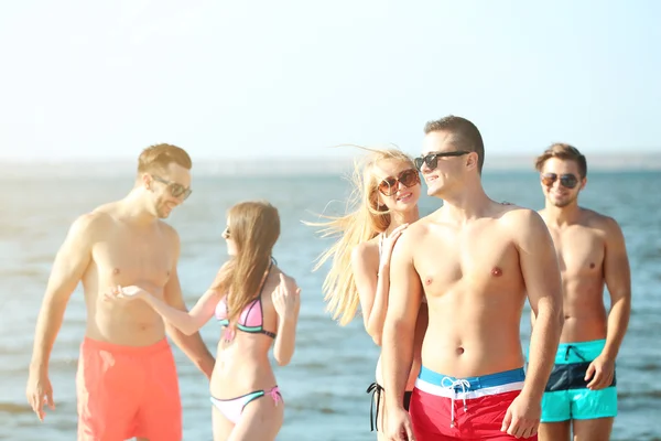 Casal feliz e amigos relaxando na praia — Fotografia de Stock