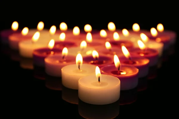 Beaucoup de petites bougies brûlantes sur fond sombre, gros plan — Photo