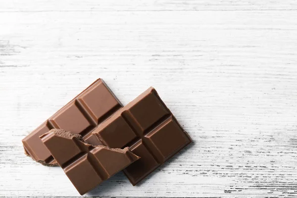 Pedaços de chocolate preto na cor de fundo de madeira — Fotografia de Stock