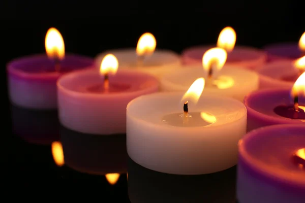 Molte piccole candele accese su sfondo scuro, primo piano — Foto Stock