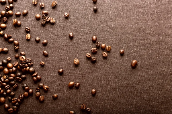 Grãos de café torrados sobre fundo têxtil cinzento — Fotografia de Stock