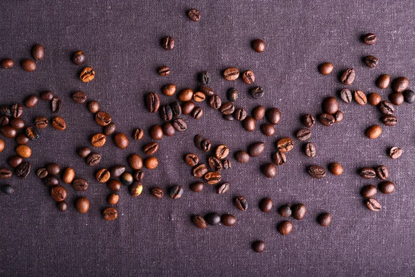 Grãos de café torrados sobre fundo têxtil cinzento — Fotografia de Stock