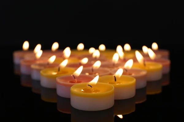Beaucoup de petites bougies brûlantes sur fond sombre — Photo