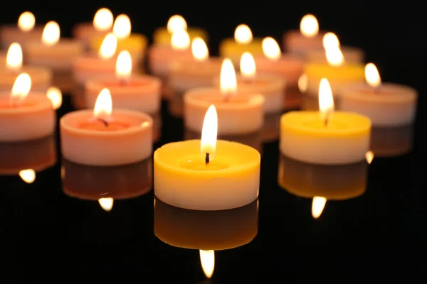 Molte piccole candele accese su sfondo scuro, primo piano — Foto Stock