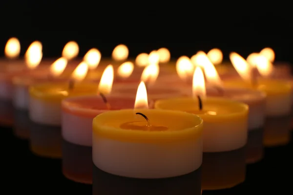 Muchas velas pequeñas ardientes sobre fondo oscuro, primer plano — Foto de Stock