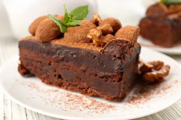 Pedaço de bolo de chocolate com noz e hortelã na mesa, close-up — Fotografia de Stock