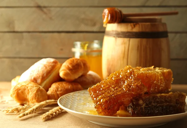 Honeycombs on plate, hot buns in basket — Stock Photo, Image