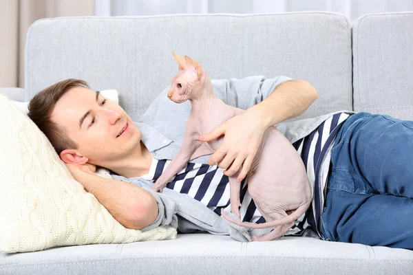 Hombre guapo se acuesta con gato en el sofá —  Fotos de Stock