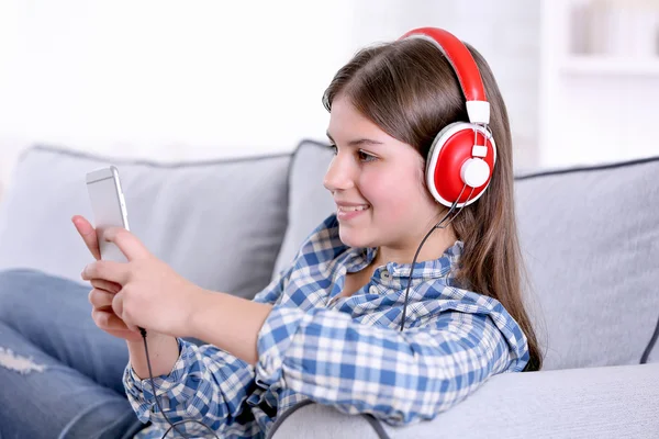 Menina bonita ouvindo música no sofá — Fotografia de Stock