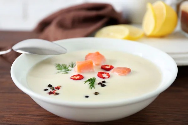 Delicious salmon cream soup with spoon on wooden table, close up — Stock Photo, Image