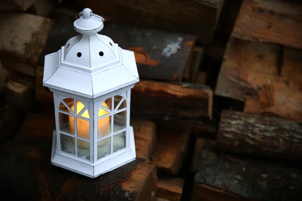 Lantern with candle on stack of firewood — Stock Photo, Image