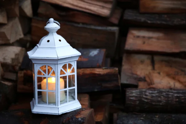 Lantern with candle on stack of firewood — Stock Photo, Image