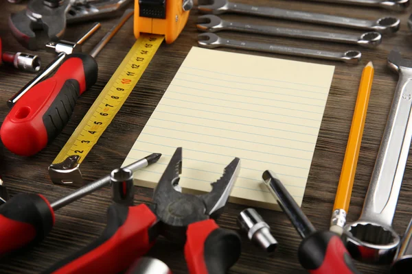 Olika typer av verktyg med en anteckningsbok på trä bakgrund, närbild — Stockfoto