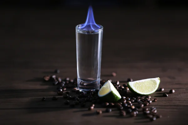 Hořící koktejl s limetkou a kávová zrna na dřevěné pozadí — Stock fotografie