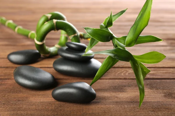 Spa stones and bamboo branch on wooden background — Stock Photo, Image