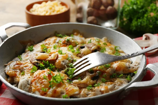 Gebratene Champignons, Hühner- und Käsegratin in der Pfanne, auf Holzgrund — Stockfoto