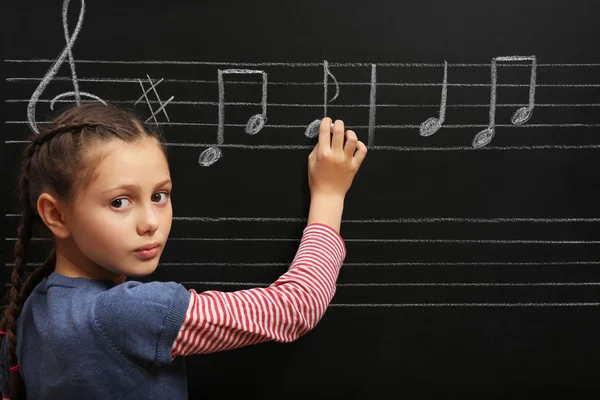 Menina escrevendo notas musicais — Fotografia de Stock