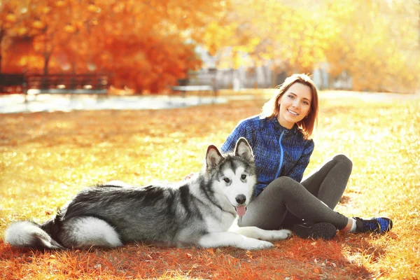 公園で彼女の犬と一緒に座っている女性 — ストック写真