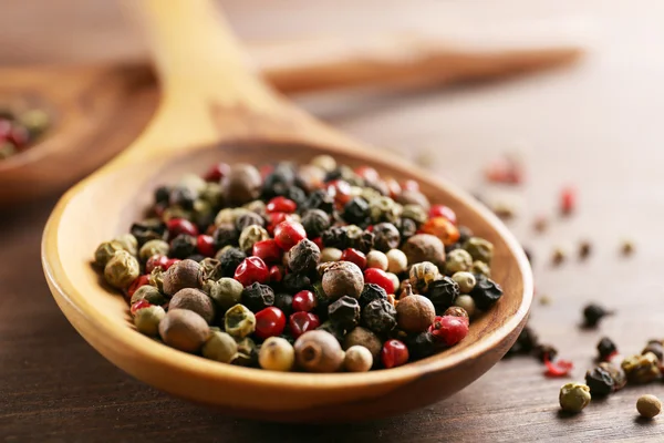 Poivre dans une cuillère en bois sur la table, gros plan — Photo