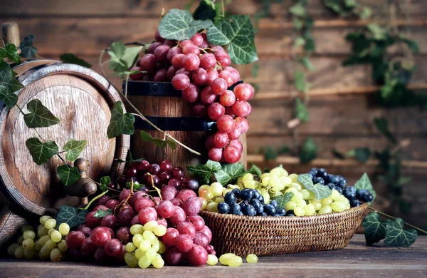 Druiven in kom en vat op houten tafel — Stockfoto