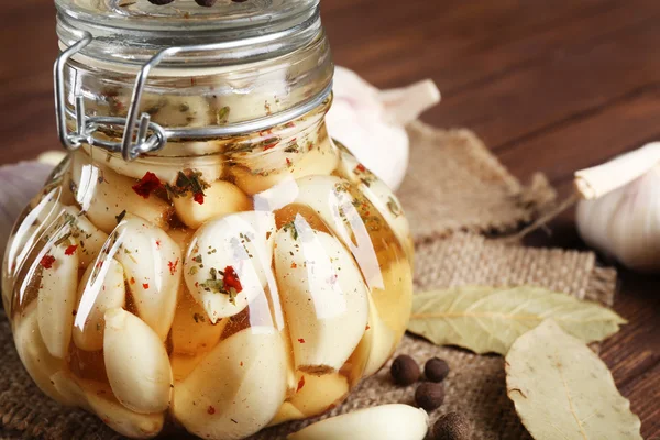 Canned garlic with spices on wooden background — Stock Photo, Image