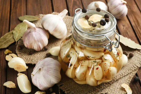 Aglio in scatola con spezie su fondo di legno — Foto Stock