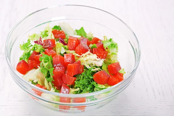 Tasty salad in glass dish on color wooden table background — Stock Photo, Image